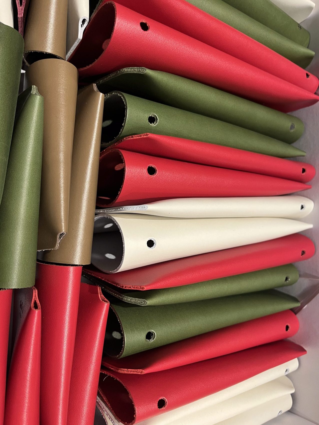 Étuis de toutes les couleurs empilés : rouge, vert, crème, taupe