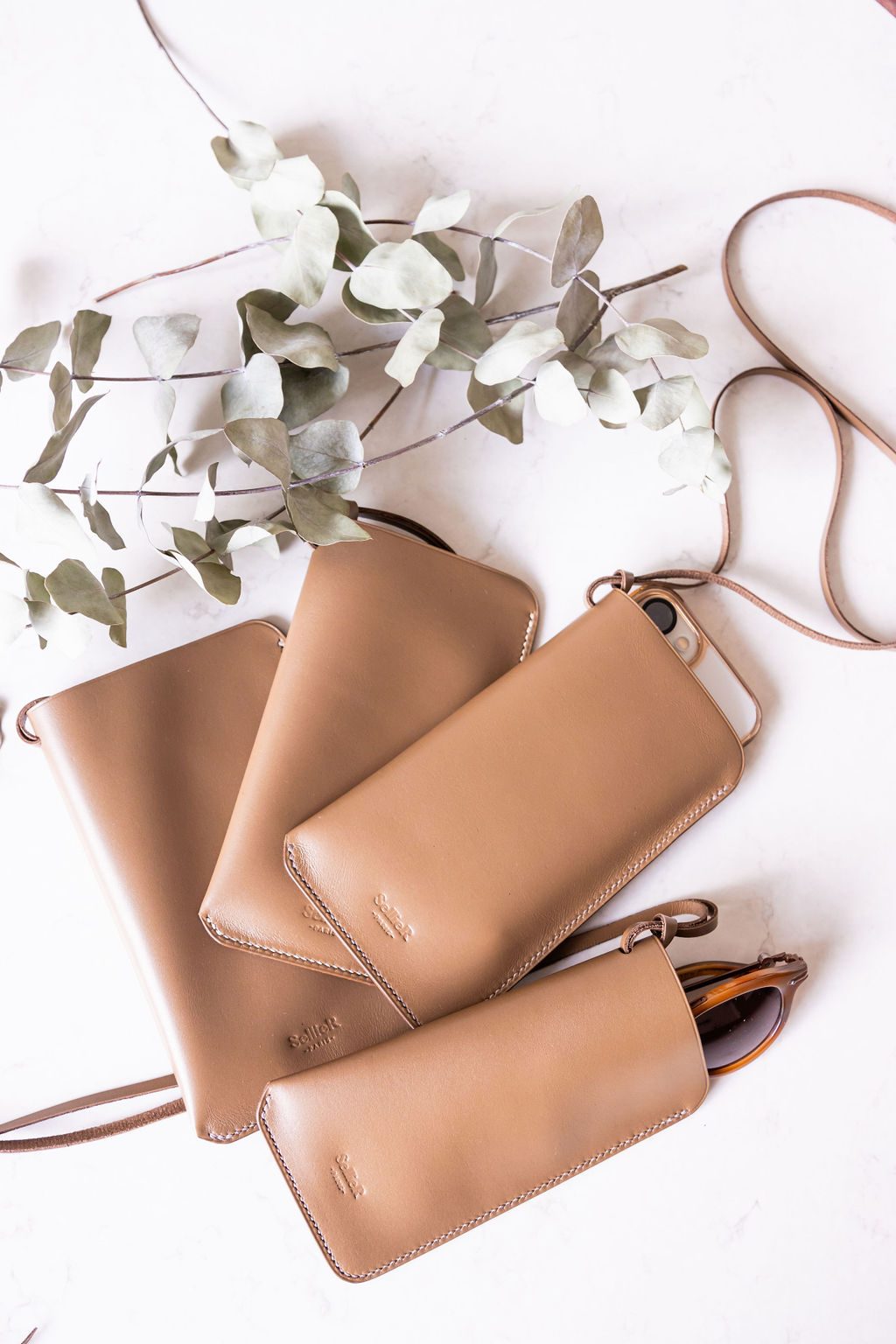 Étuis Maxi en cuir taupe parmi l'eucalyptus