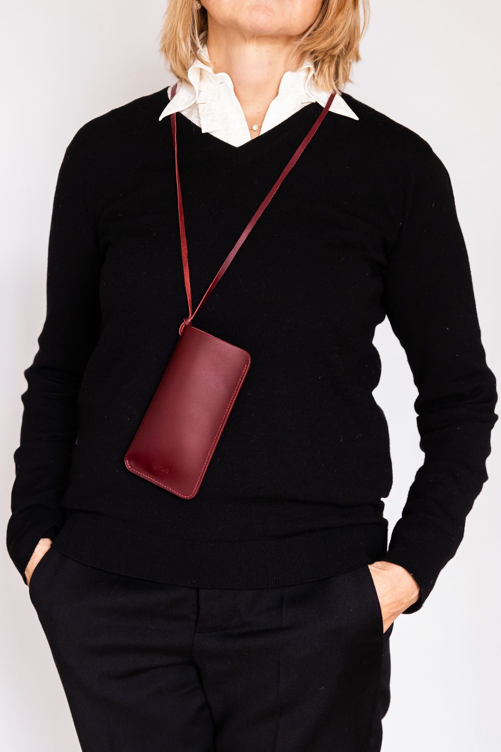 Étui bordeaux porté sur un pull noir