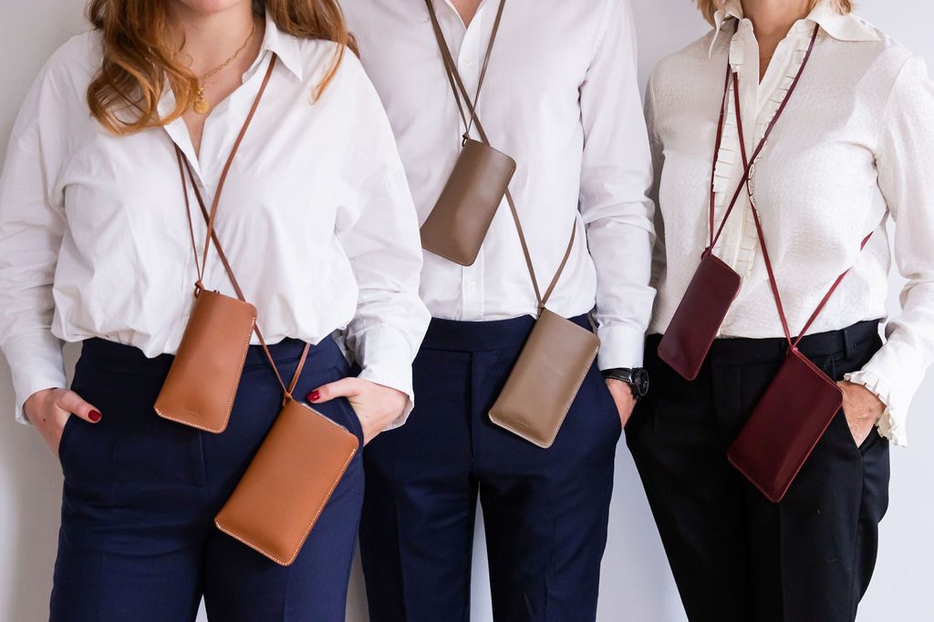 Trois personnes en chemise blanche portant des étuis cognac, taupe et bordeaux