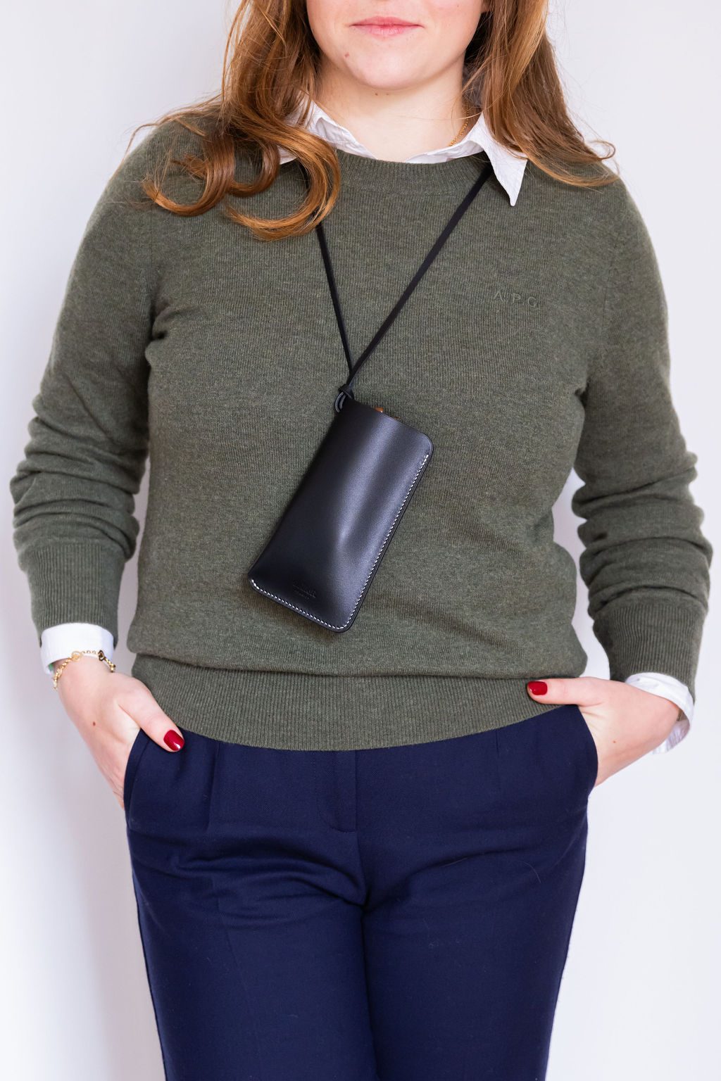 Étui noir porté sur un pull vert